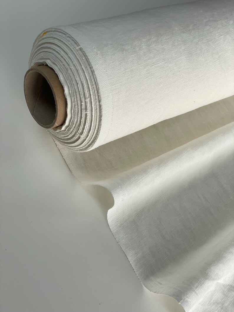 May include: A roll of white linen fabric. The fabric is tightly rolled and has a natural, slightly textured surface.