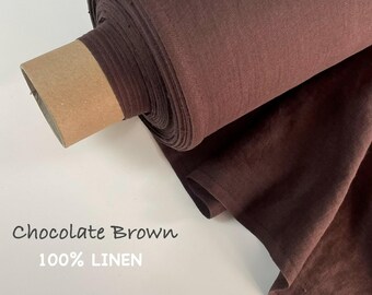 Op de afbeelding: Een rol chocoladebruine stof gemaakt van 100% linnen. De stof is om een kartonnen koker gewikkeld, waarbij een deel van het materiaal is uitgerold en gedrapeerd. De tekst Chocolate Brown 100% LINEN staat linksonder afgedrukt.