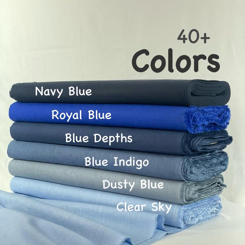 May include: A stack of six fabric bolts in various shades of blue, labeled Navy Blue, Royal Blue, Blue Depths, Blue Indigo, Dusty Blue, and Clear Sky. The text 40+ Colors is displayed above the fabric stack, which features a textured weave.