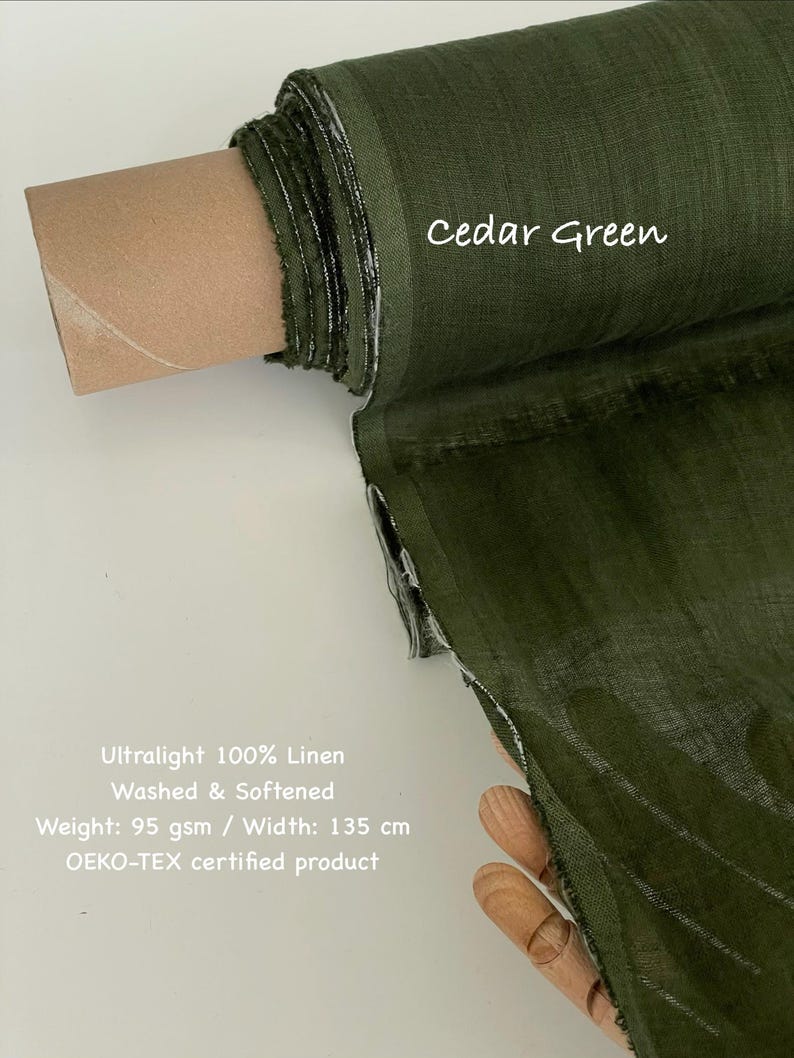 May include: A roll of cedar green ultralight 100% linen fabric. The fabric is washed and softened, with a weight of 95 gsm and a width of 135 cm. The text "Cedar Green" is written on the fabric.
