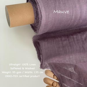 May include: A roll of mauve-colored ultralight 100% linen fabric. The fabric is softened and washed, with a weight of 95 gsm and a width of 135 cm. The text "Mauve" is visible on the fabric. The product is OEKO-TEX certified.