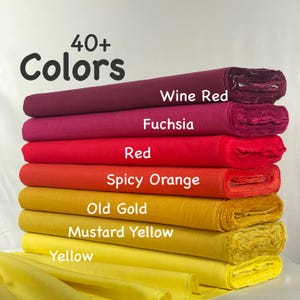 May include: A stack of fabric bolts in a gradient of colors including wine red, fuchsia, red, spicy orange, old gold, mustard yellow, and yellow. The text 40+ Colors is printed at the top, with labels identifying each specific fabric shade.