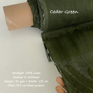 May include: A roll of cedar green ultralight 100% linen fabric. The fabric is washed and softened, with a weight of 95 gsm and a width of 135 cm. The text "Cedar Green" is displayed on the fabric.