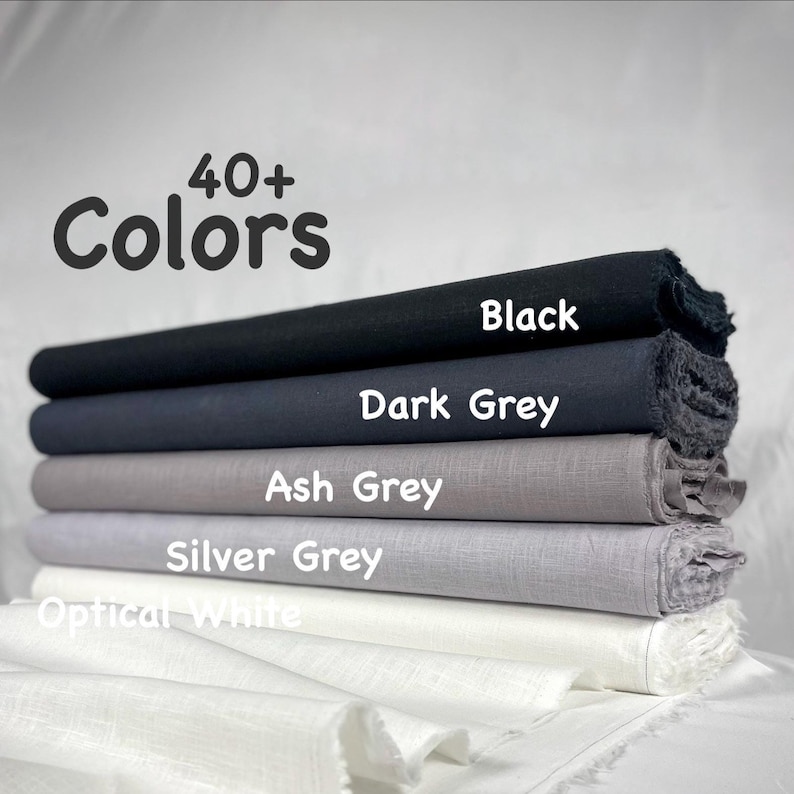 K&ouml;nnte beinhalten: Ein Stapel aus f&uuml;nf gefalteten Stoffballen in einem Farbverlauf, beschriftet mit dem Text 40+ Colors. Die Stofffarben von oben nach unten sind Black, Dark Grey, Ash Grey, Silver Grey und Optical White, alle mit einer sichtbaren Webstruktur.