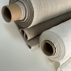May include: Two rolls of natural linen fabric. One roll is a light beige color and the other is a bright white.