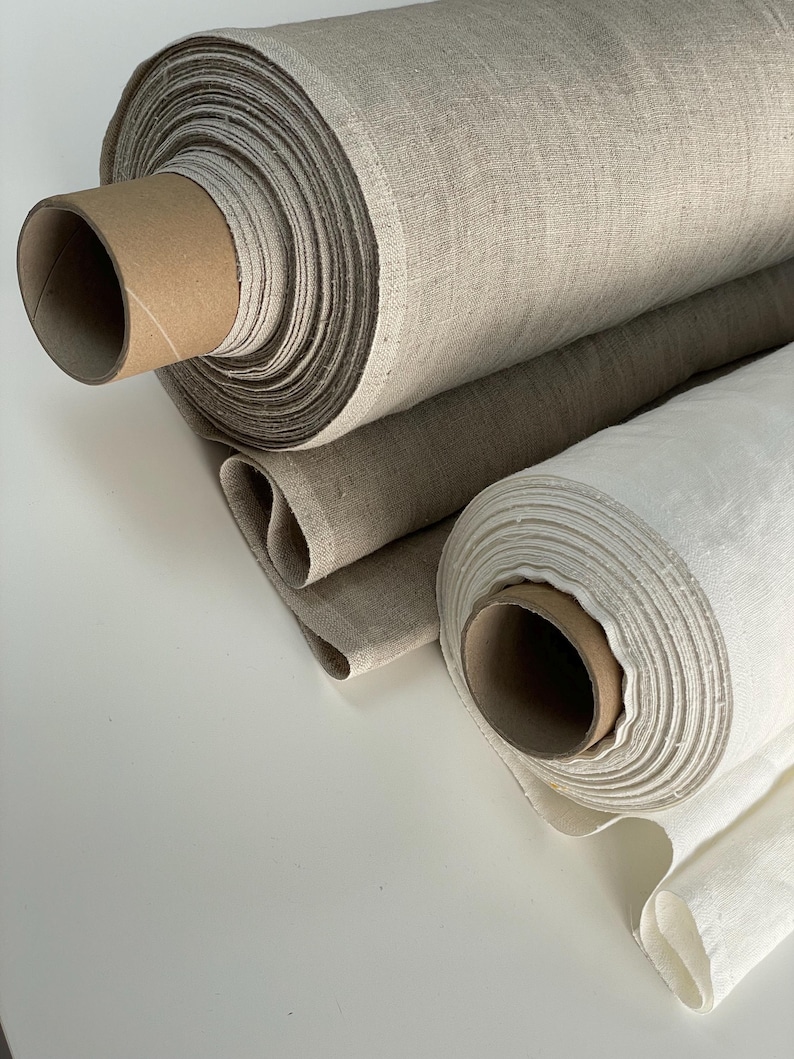 May include: Two rolls of natural linen fabric. One roll is a light beige color and the other is a bright white.