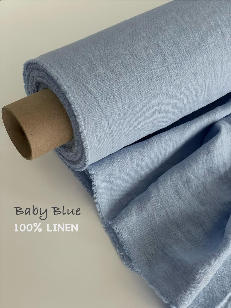 May include: A roll of baby blue 100% linen fabric with a visible woven texture and frayed edges. The fabric is wrapped around a brown cardboard tube. The text Baby Blue 100% LINEN is printed on the left side of the image in a simple font.