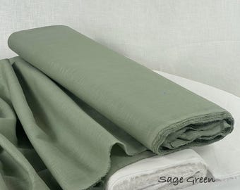 Op de afbeelding: Een rol saliegroene 100% linnen stof met een zichtbare geweven textuur. De stof is gevouwen en gedrapeerd en heeft een zachte, matte afwerking. De tekst "Sage Green 100% Linen Fabric" staat rechtsonder op de rol gedrukt.
