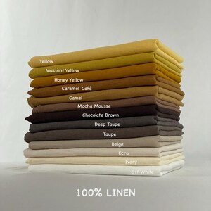 Może przedstawiać: Stos złożonych pr&oacute;bek tkanin ze 100% lnu w r&oacute;żnych odcieniach, w tym Yellow, Mustard Yellow, Honey Yellow, Caramel Caf&eacute;, Camel, Mocha Mousse, Chocolate Brown, Deep Taupe, Taupe, Beige, Ecru, Ivory i Off White z odpowiednimi etykietami.