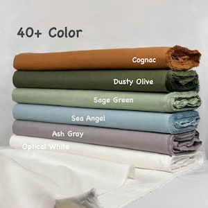 May include: A stack of six folded fabric bolts in various colors labeled 40+ Color, Cognac, Dusty Olive, Sage Green, Sea Angel, Ash Gray, and Optical White. Each bolt features a textured weave with frayed edges, arranged horizontally in a vertical pile.