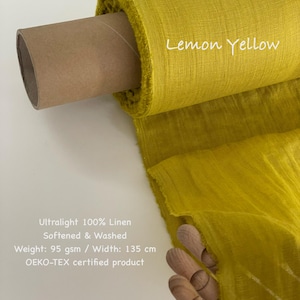 Op de afbeelding: Een rol citroengele ultralichte 100% linnen stof. De stof is verzacht en gewassen, met een gewicht van 95 g/m&sup2; en een breedte van 135 cm. De tekst "Lemon Yellow" staat op de stof.