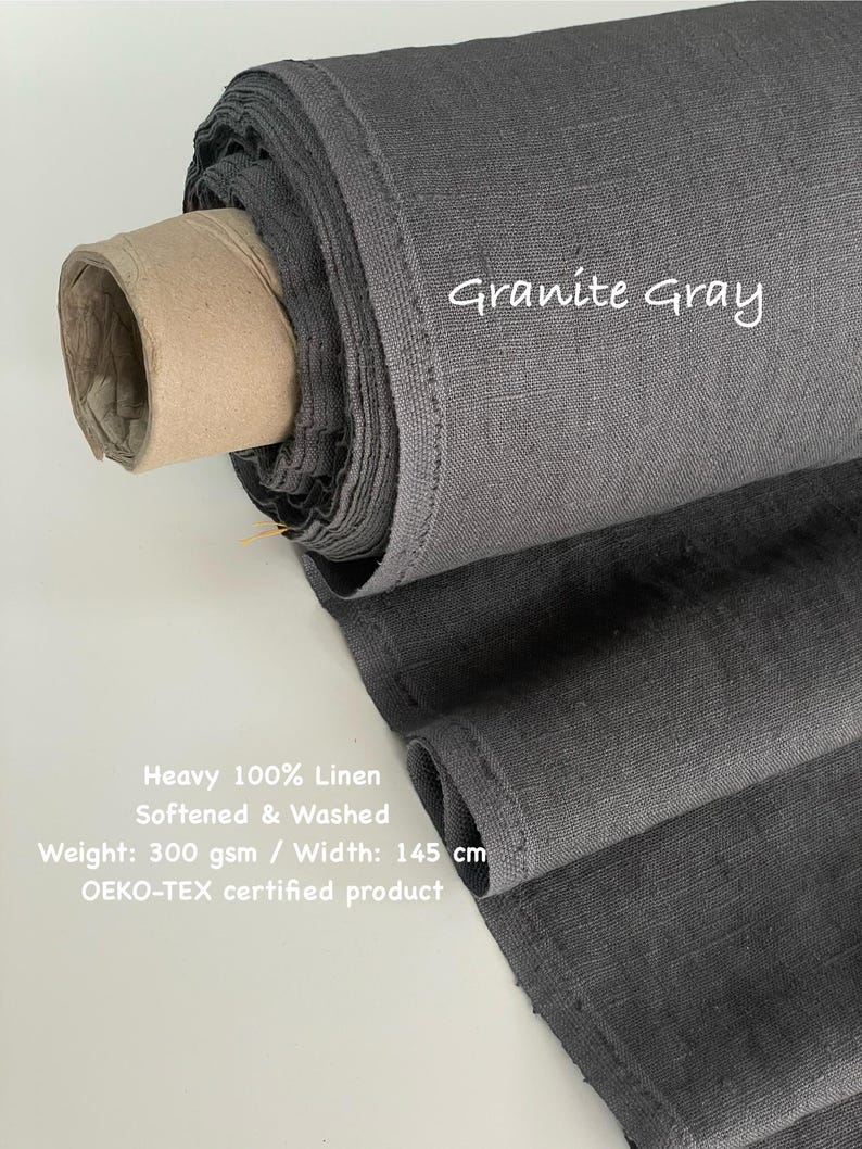 May include: A roll of heavy, softened, and washed 100% linen fabric in Granite Gray. The fabric has a weight of 300 gsm and a width of 145 cm. The text "Granite Gray" is written on the fabric. The product is OEKO-TEX certified.