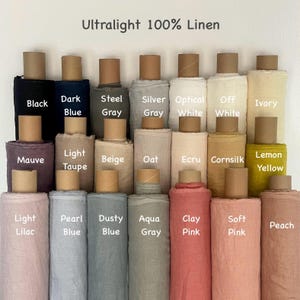 May include: A display of various colors of ultralight 100% linen fabric rolls. Colors include black, dark blue, steel gray, silver gray, optical white, off white, ivory, mauve, light taupe, beige, oat, ecru, cornsilk, lemon yellow, light lilac, pearl blue, dusty blue, aqua gray, clay pink, soft pink, and peach.