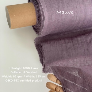 May include: A roll of mauve-colored ultralight 100% linen fabric. The fabric is softened and washed, with a weight of 95 gsm and a width of 135 cm. The text "Mauve" is visible on the fabric. The product is OEKO-TEX certified.