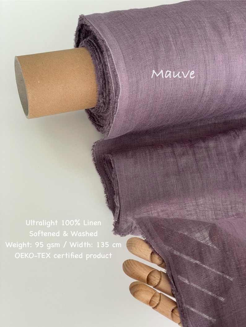 May include: A roll of mauve-colored ultralight 100% linen fabric. The fabric is softened and washed, with a weight of 95 gsm and a width of 135 cm. The text "Mauve" is visible on the fabric. The product is OEKO-TEX certified.