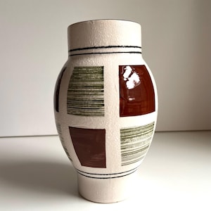 May include: A white ceramic mug with a black handle and the text "But First, Coffee" in a black, bold font. The mug is on a white surface. The mug is likely 11 ounces.
