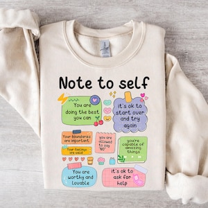 Może przedstawiać: Kremowa bluza z napisem "Note to self" i kolorowymi ilustracjami. Projekt zawiera pozytywne afirmacje, takie jak "You are doing the best you can" i "It's ok to start over and try again."