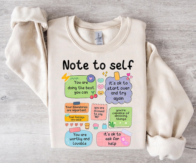Może przedstawiać: Kremowa bluza z napisem "Note to self" i kolorowymi ilustracjami. Projekt zawiera pozytywne afirmacje, takie jak "You are doing the best you can" i "It's ok to start over and try again."