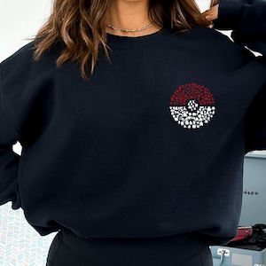 May include: Black sweatshirt with a red and white Pokeball graphic made of smaller Pokeball icons.