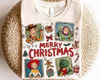 May include: Cream-colored t-shirt featuring a festive design with characters from Toy Story. The design includes Woody, Buzz Lightyear, Jessie, and Rex, along with Christmas-themed elements and the words "MERRY CHRISTMAS" in red.