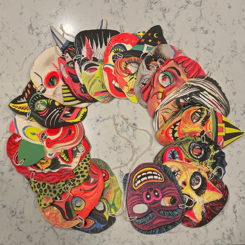 Pu&ograve; includere: Una collezione di maschere di Halloween vintage con vari disegni colorati e dettagliati. Le maschere sono fatte di carta e presentano personaggi come mostri, fantasmi e streghe.