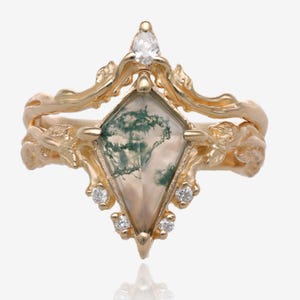 Op de afbeelding: Een gouden ring met een mossa-agaten edelsteen gezet in een delicaat, bladerig ontwerp. De ring is versierd met kleine diamanten.