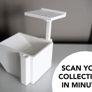 3D-printed white trading card scanner and dispenser tray with a built-in phone stand. Designed for TCG, MTG, Pokémon, and Lorcana, allowing easy card scanning with apps like Manabox, TCGPlayer, and Delver Lens. Perfect for collectors and sellers.