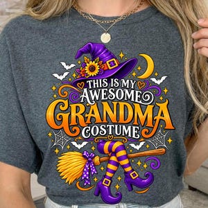 May include: A dark heather grey t-shirt featuring a graphic of a purple witch hat with a sunflower, a yellow crescent moon, white bats, spiderwebs, and a broomstick with purple and yellow striped stockings and purple boots, with the text THIS IS MY AWESOME GRANDMA COSTUME.
