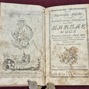 Può includere: Un libro antico aperto, con pagine ingiallite e invecchiate. La pagina sinistra presenta un'illustrazione dettagliata di Maria che tiene in braccio Gesù bambino e una scena di paesaggio. La pagina destra mostra un testo ornato in tedesco, con il titolo "Marianische Andacht".
