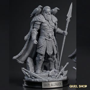 May include: A grey resin figurine of a bearded warrior wearing armor and a fur-lined cloak, holding a long spear. Two ravens sit on the shoulders. The base features scattered weapons and a plaque with the text ODIN: ALLFADER in capital letters.