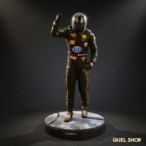 May include: A figurine of a race car driver in a black and gold racing suit, helmet, and gloves, standing on a round base. The driver is raising a fist in a celebratory gesture. The base has a silver and black design.