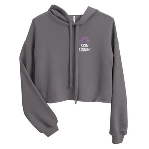 May include: A gray cropped hoodie with a purple rainbow and white clouds graphic and the text "SKIN SHININ'" on the front.