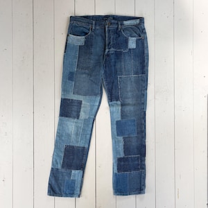 May include: Denim jeans in shades of blue with a patchwork design. The jeans are constructed from various denim patches, creating a textured effect. They have a classic five-pocket design and a button fly. The jeans are a stylish garment.