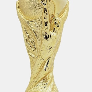 May include: A gold trophy featuring a globe and two figures, set on a green base with gold lettering that reads 'FIFA WORLD CUP'. A symbol of sporting achievement and international competition.