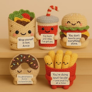 Peut inclure: Ensemble de cinq aliments crochetés : un burrito, un soda, un burger, un beignet et des frites. Chaque article a un visage souriant et une petite pancarte avec un message. Le burrito dit "Wrap yourself in love, Annie."
