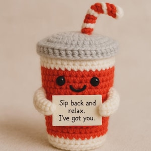 Peut inclure: Une tasse à boisson rouge et blanche au crochet avec un couvercle gris et une paille rayée rouge et blanche. La tasse a un visage souriant et tient une pancarte avec l'inscription "Sip back and relax. I've got you."