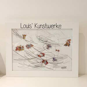 Könnte beinhalten: Ein gerahmtes Kunstwerk mit einer Kinderzeichnung mit bunten Charakteraufklebern. Der weiße Rahmen umgibt eine Zeichnung mit gekritzelten Linien und mehreren Charakteraufklebern. Der Text "Louis' Kunstwerke" ist oben auf dem Rahmen aufgedruckt.