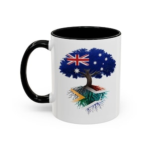 Peut inclure: Un mug en céramique blanche avec une anse et un intérieur noirs. L'extérieur présente un graphique d'arbre dont le feuillage affiche le drapeau australien et les racines s'étendent dans un sol aux couleurs du drapeau national sud-africain.