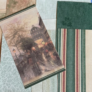 May include: A collection of decorative paper sheets featuring various patterns including a rectangular print of a rainy city street scene with a clock, dark green textured paper, striped paper with red and green, and floral beige paper.