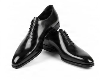 May include: A pair of polished black leather oxford shoes featuring a sleek, pointed toe design, a closed lacing system with thin black laces, and a low stacked heel. The shoes have a smooth, glossy finish and a structured silhouette.