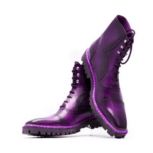 May include: A pair of purple leather boots with lace-up closures and a contrasting pink stitching detail. The boots have a chunky sole and a pointed toe.