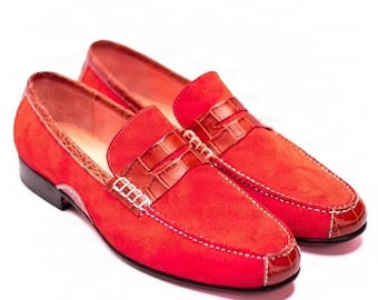 Könnte beinhalten: Ein Paar leuchtend rote Slipper mit einer Wildledertextur am Hauptteil und einem glänzenden, geprägten Krokodillederbesatz. Die Schuhe verfügen über einen klassischen Penny-Loafer-Riemen über dem Vorderblatt, der mit sichtbaren weißen Nähten akzentuiert ist.