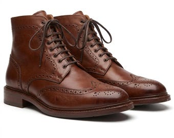 May include: A pair of brown leather ankle boots featuring a classic wingtip design with decorative brogue perforations along the seams, a rounded toe, and dark brown laces threaded through metal eyelets on a high-cut lace-up closure system.