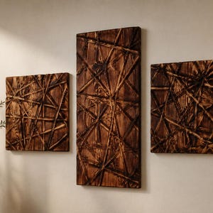 May include: Three wooden wall art panels with a geometric, linear design. The panels are rectangular and square, with a dark brown finish. The artwork is mounted on a light-coloured wall, creating a contrast. The panels are arranged in a group.