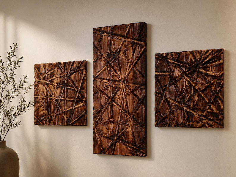 May include: Three wooden wall art panels with a geometric, linear design. The panels are rectangular and square, with a dark brown finish. The artwork is mounted on a light-coloured wall, creating a contrast. The panels are arranged in a group.