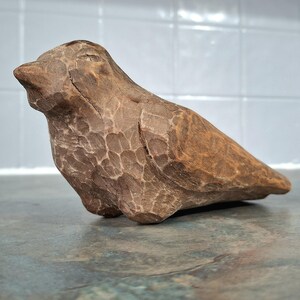 Pu&ograve; includere: Scultura di uccello in legno intagliato a mano, nei toni del marrone. L'uccello ha una superficie strutturata con un motivo dettagliato. La scultura &egrave; un oggetto decorativo, probabilmente per l'arredamento della casa.