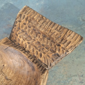Pu&ograve; includere: Primo piano di una ciotola di legno intagliata a mano. La ciotola ha una finitura naturale con venature del legno e un design strutturato e modellato sul bordo. L'interno della ciotola &egrave; liscio, in contrasto con l'esterno dettagliato.