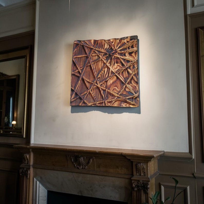 May include: A square wooden artwork with a textured geometric design. The piece features intersecting lines and shapes, with a warm brown colour. The wood grain is visible, enhancing the natural aesthetic of the wall art.