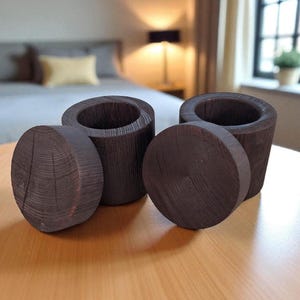 May include: Four dark brown wooden containers with lids, displayed on a light brown table. Two are cylindrical with open tops, and two are circular lids. The wood grain is visible, suggesting a handcrafted item.