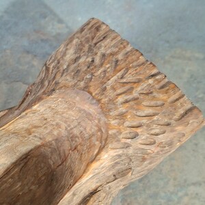 Pu&ograve; includere: Primo piano di una scultura in legno intagliata a mano. La scultura ha una superficie ruvida e strutturata con un motivo a venature naturali del legno. Il legno &egrave; di un caldo colore marrone chiaro con accenti pi&ugrave; scuri.